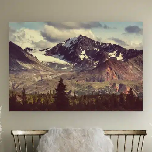 Besneeuwde bergtop aan de muur boven een houten bankje met schapenvacht