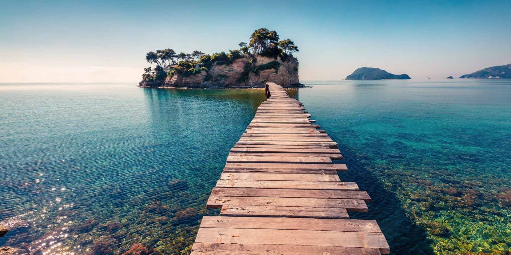 Cameo Island: houten vlonder naar een rotseilandje in turkoois water, los op wit