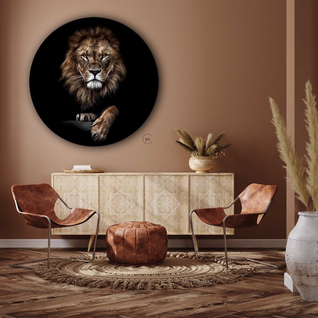 Muurcirkel leeuw boven een licht houten dressoir met twee leren stoelen tegen een terracotta muur