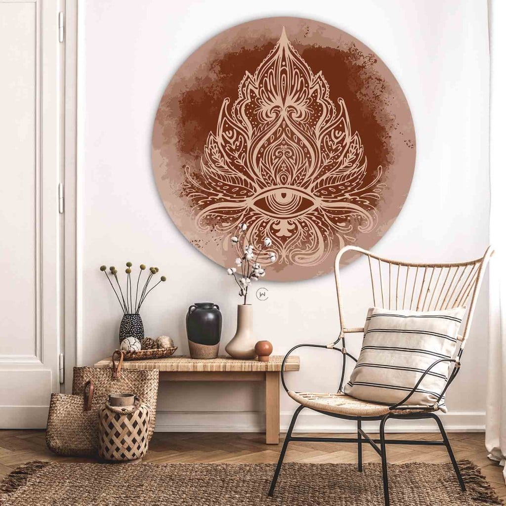 Muurcirkel boho ornament boven een rotan stoel en een houten bankje met manden tegen een witte muur