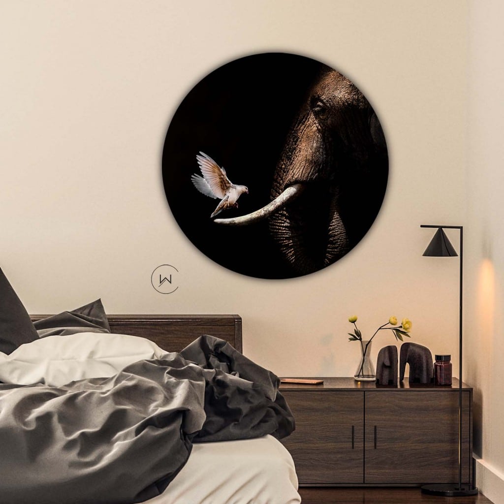 Muurcirkel olifant met duif boven een bed en een donkerhouten nachtkastje