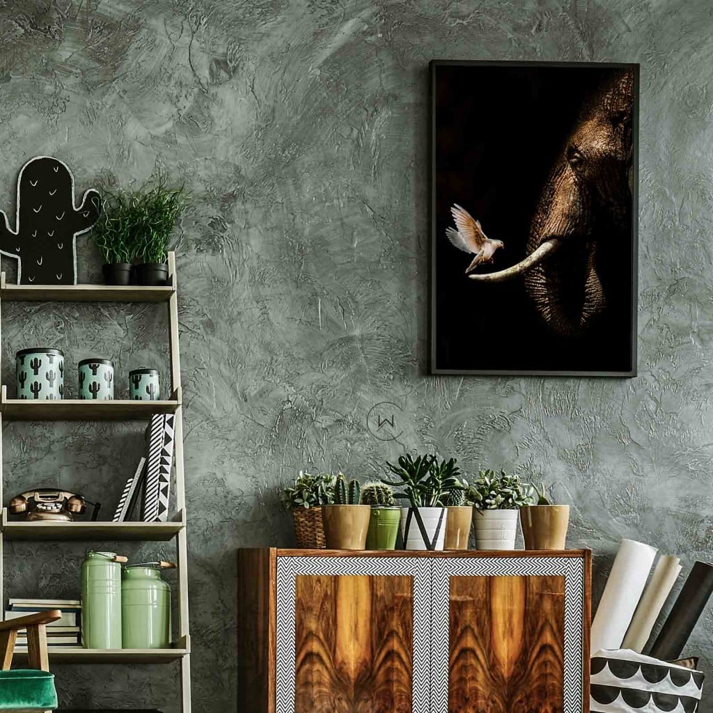 Olifant met duif in een zwarte lijst boven een houten kastje met cactussen