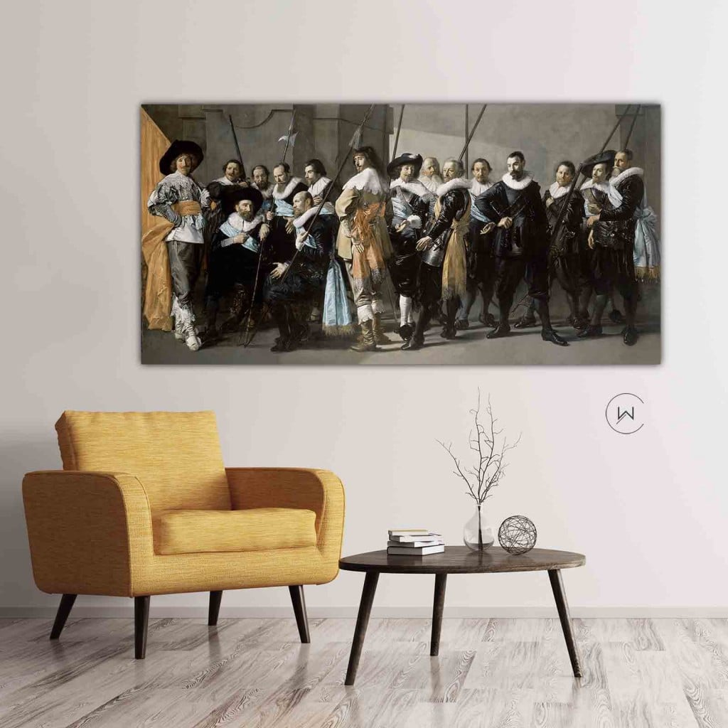 De magere compagnie aan een witte muur boven een okergele fauteuil en een zwart bijzettafeltje