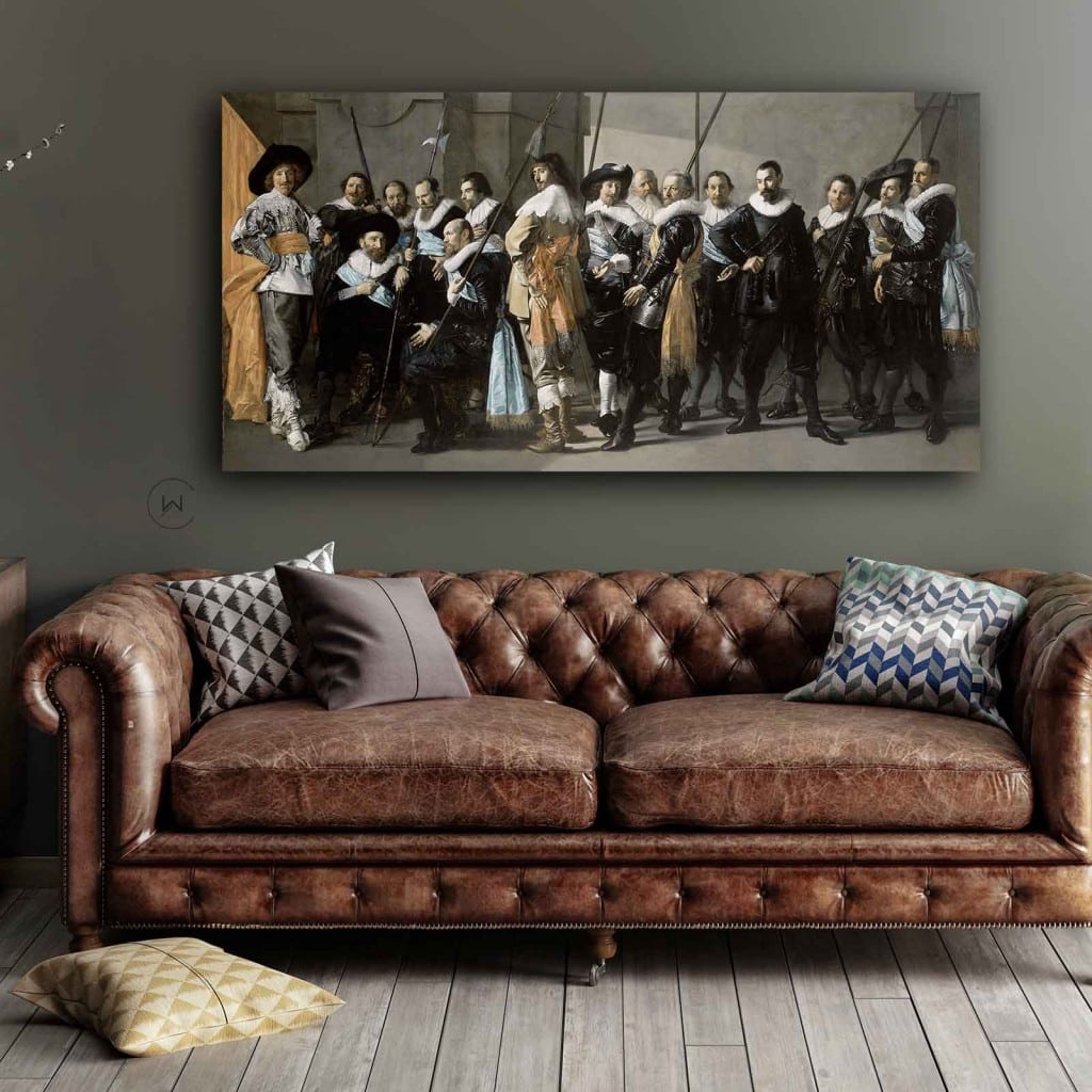 De magere compagnie van Frans Hals aan een grijze muur boven een bruine leren chesterfield