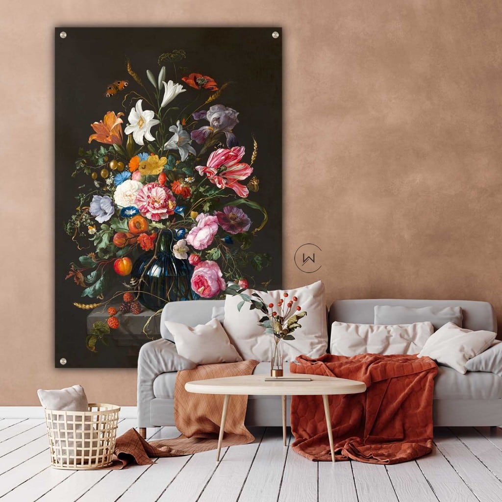 Vaas met bloemen boven een lichtgrijze bank met roestoranje plaids aan een zalmroze muur