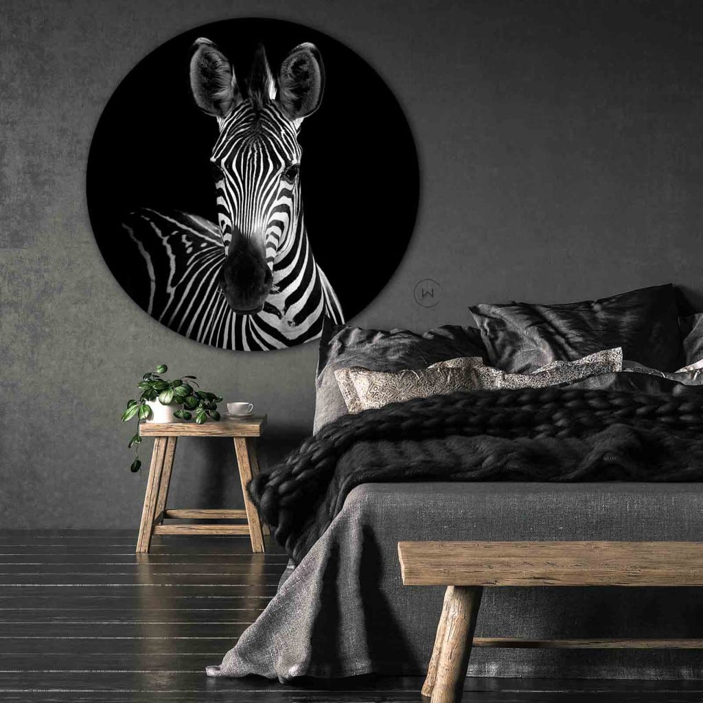 Muurcirkel zebra portret aan een donkergrijze wand boven een bed met grijs beddengoed