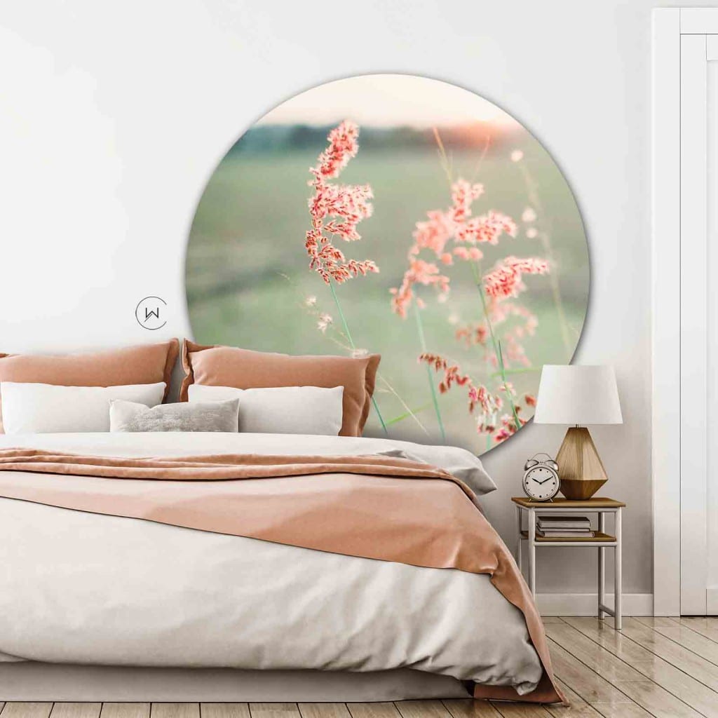 Muurcirkel roze gras aan een witte wand in de slaapkamer boven een bed met roze kussens