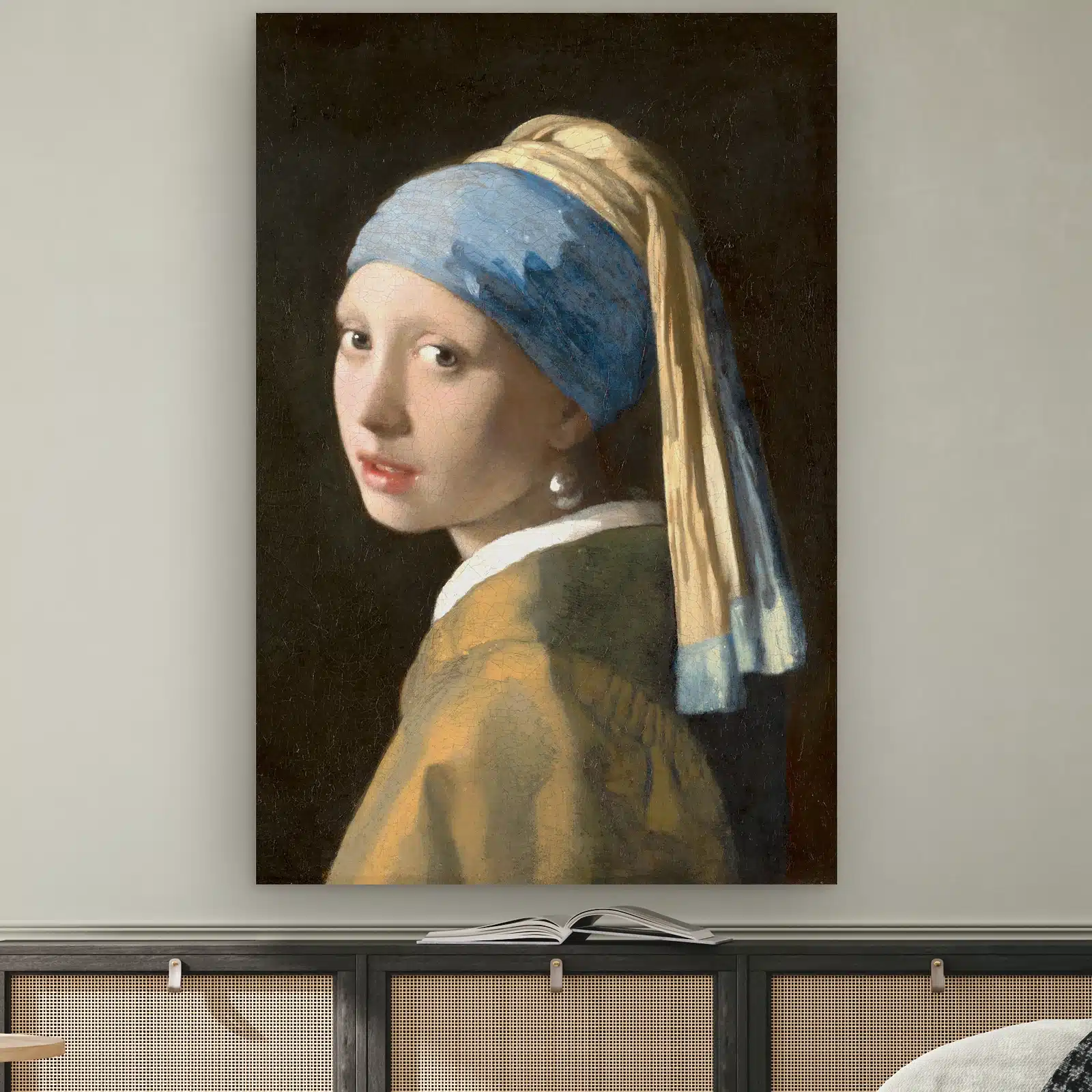 Het meisje met de parel van Johannes Vermeer aan de muur boven een dressoir met rotan deurtjes
