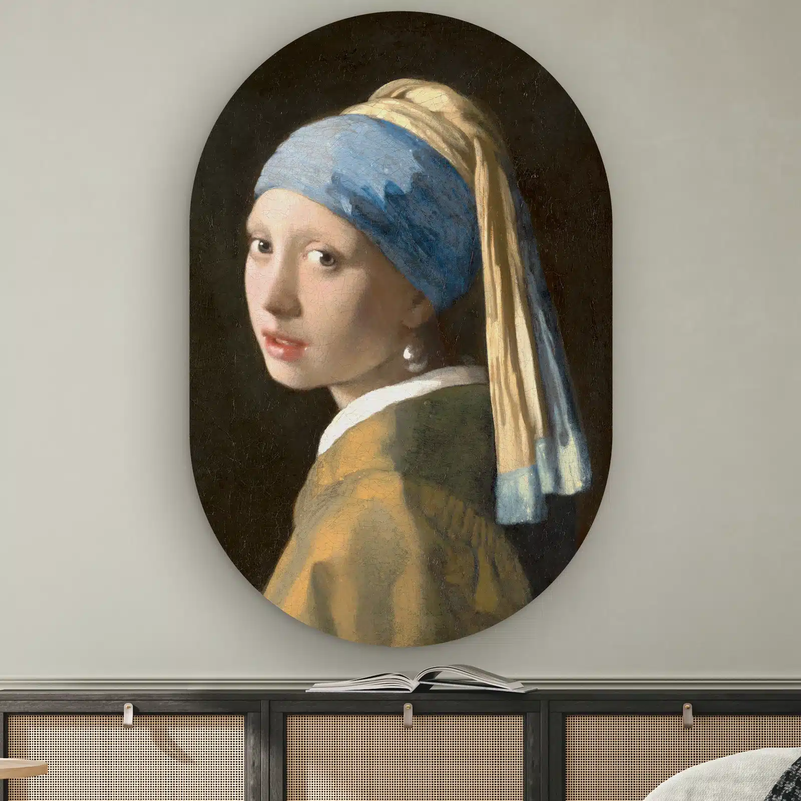 Klassiek schilderij Meisje met de parel van Vermeer als muurovaal boven een dressoir met rotan deurtjes
