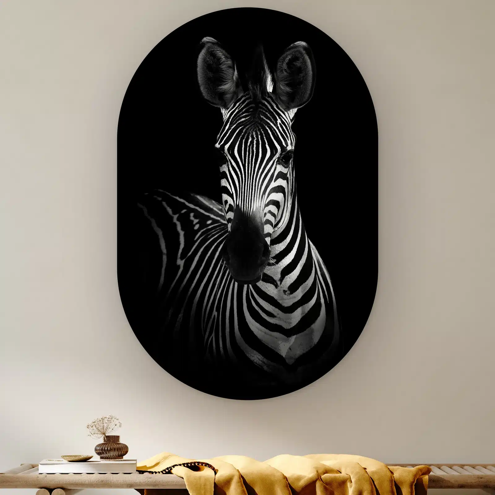 Muurovaal Zebra portret aan de muur boven een houten bank met een okergele plaid