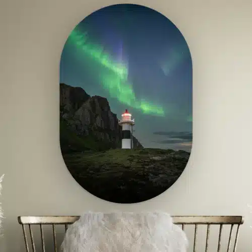 Muurovaal Noorderlicht vuurtoren Lofoten aan de muur boven een houten bankje met schapenvacht