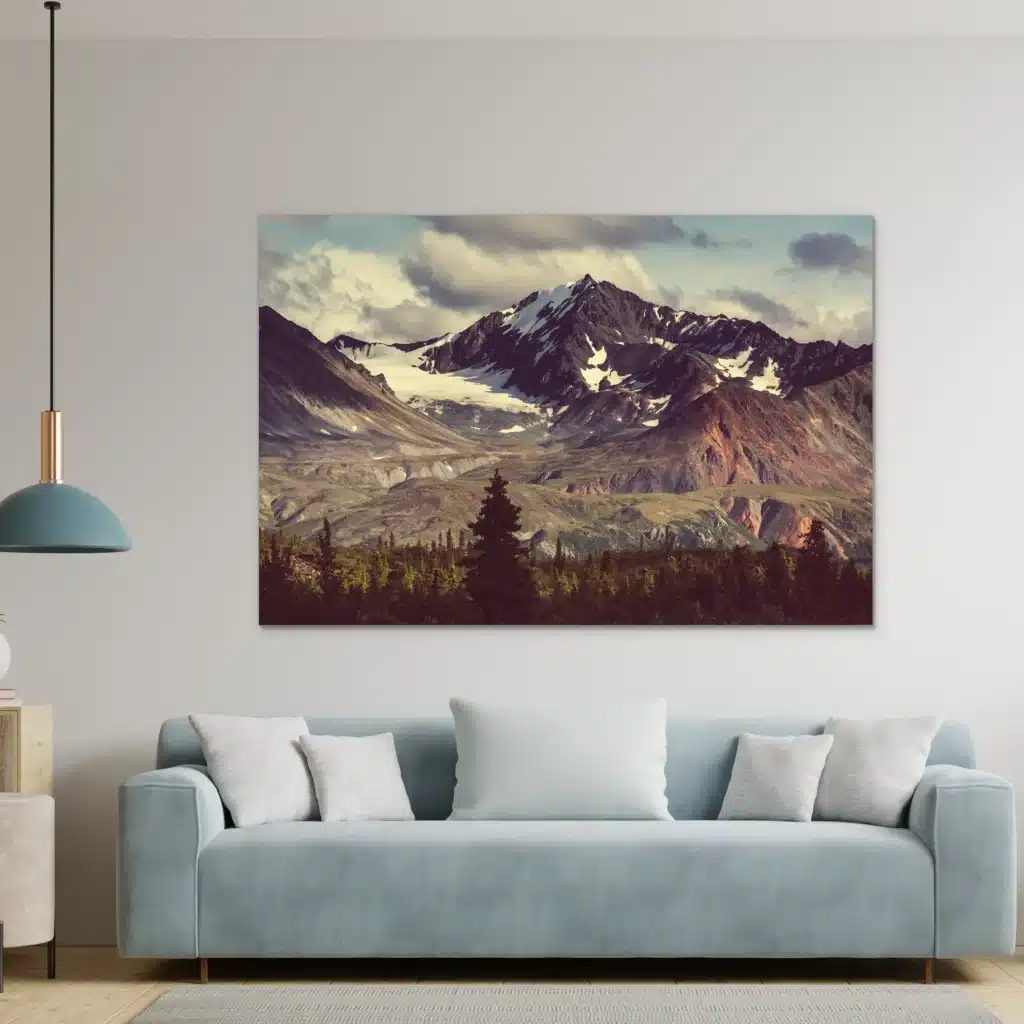 Besneeuwde bergtop boven een lichtblauwe bank met witte kussens en een hanglamp