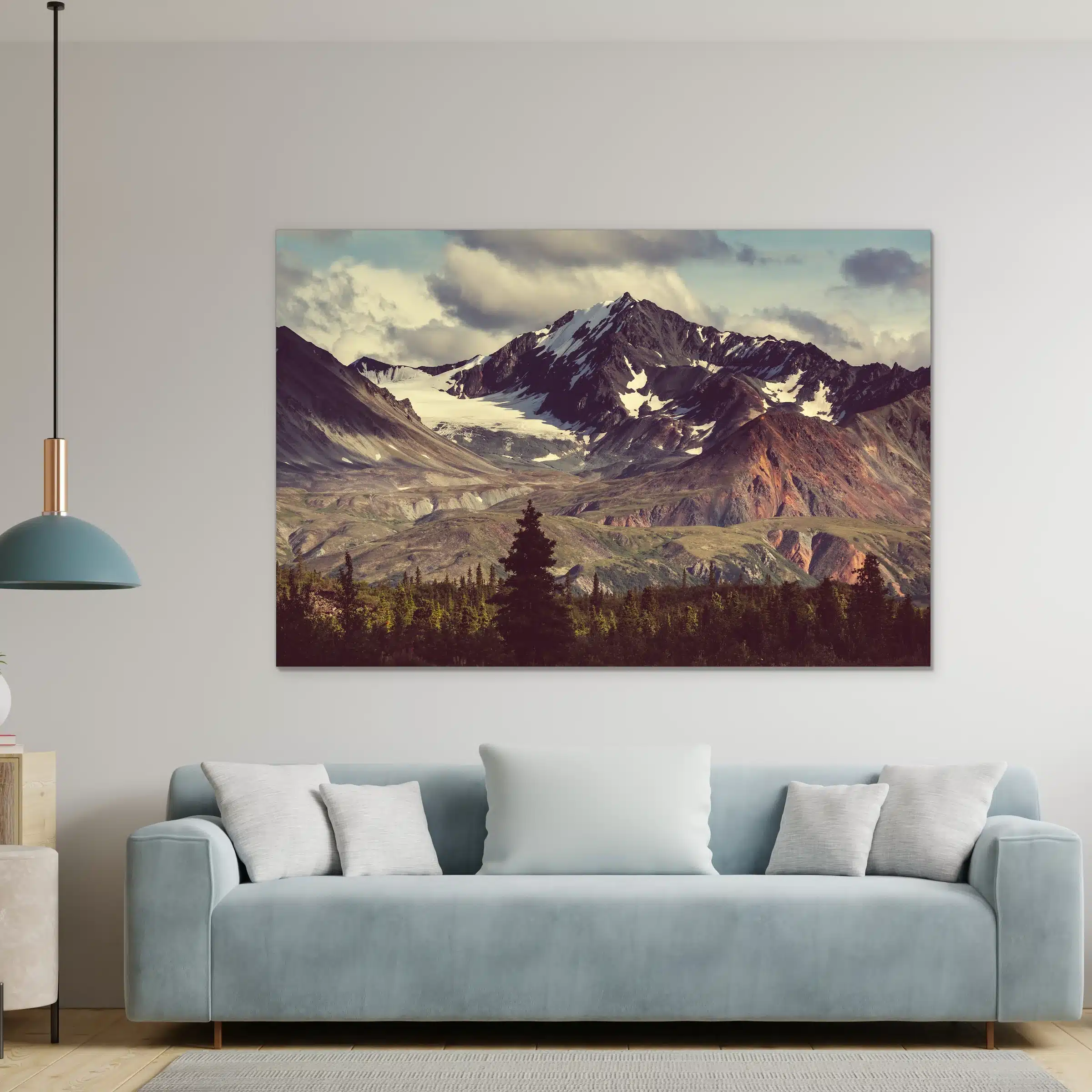 Besneeuwde bergtop boven een lichtblauwe bank met witte kussens en een hanglamp