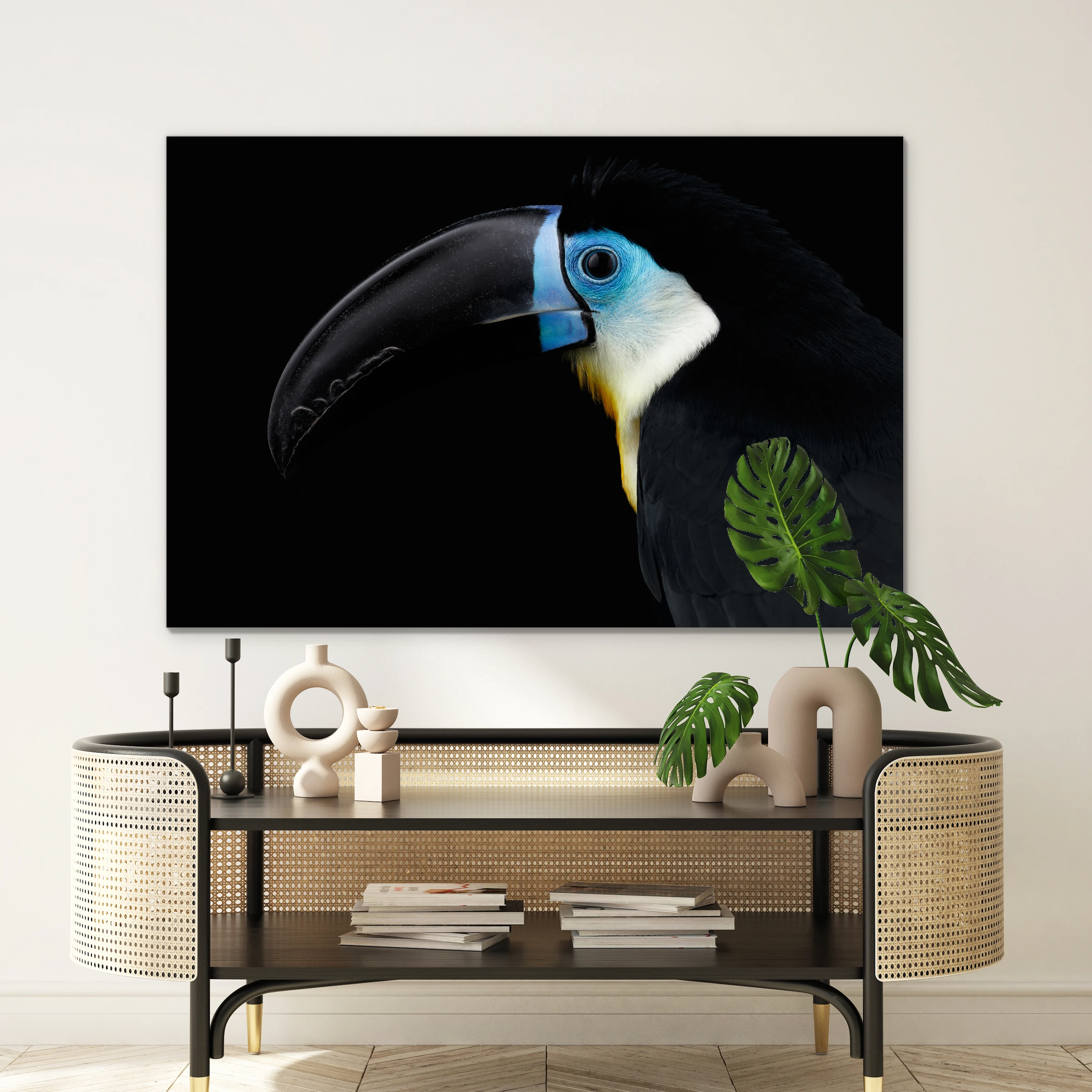 Blauwe toekan aan een witte muur boven een rotan console met een monstera