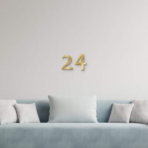 Decoratieletters 24 in goud geborsteld aluminium aan de muur boven een bank