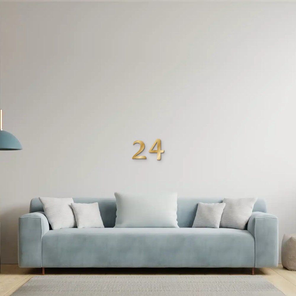 Decoratieletter in goud geborsteld aluminium aan de muur boven een bank