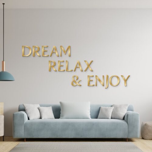 Dream Relax & Enjoy in goud geborsteld aluminium aan de muur boven een bank