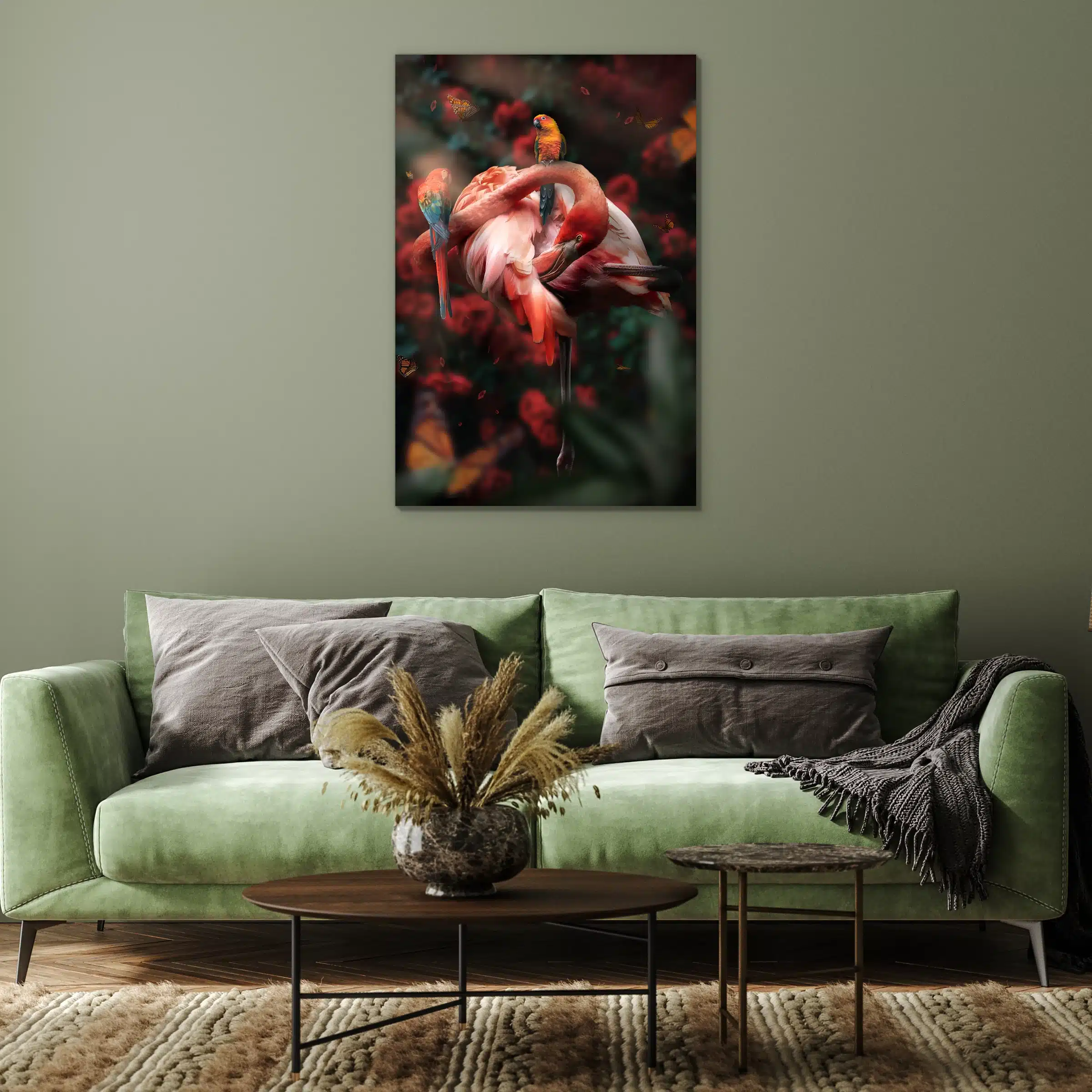 Flamingo met rozen en twee papegaaien aan een saliegroene muur boven een groene bank met grijze kussens