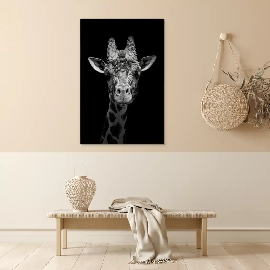 Giraf portret in zwart-wit aan een beige muur boven een geweven bankje
