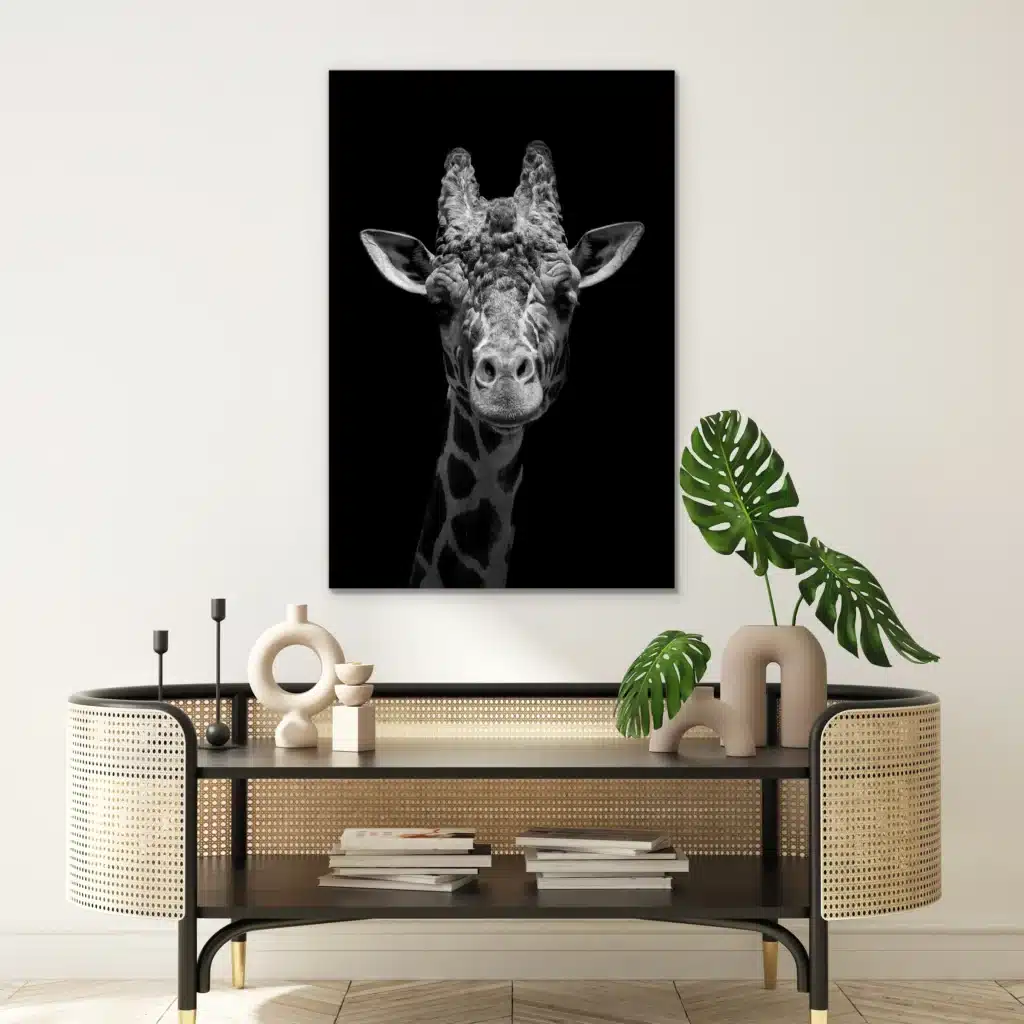 Giraf portret aan een witte muur boven een rotan console met een monstera