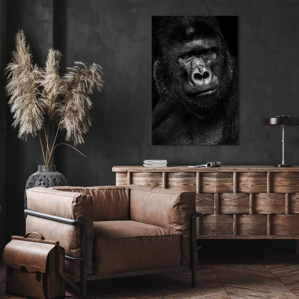 Gorilla portret aan een donkere muur boven een houten dressoir en een leren fauteuil
