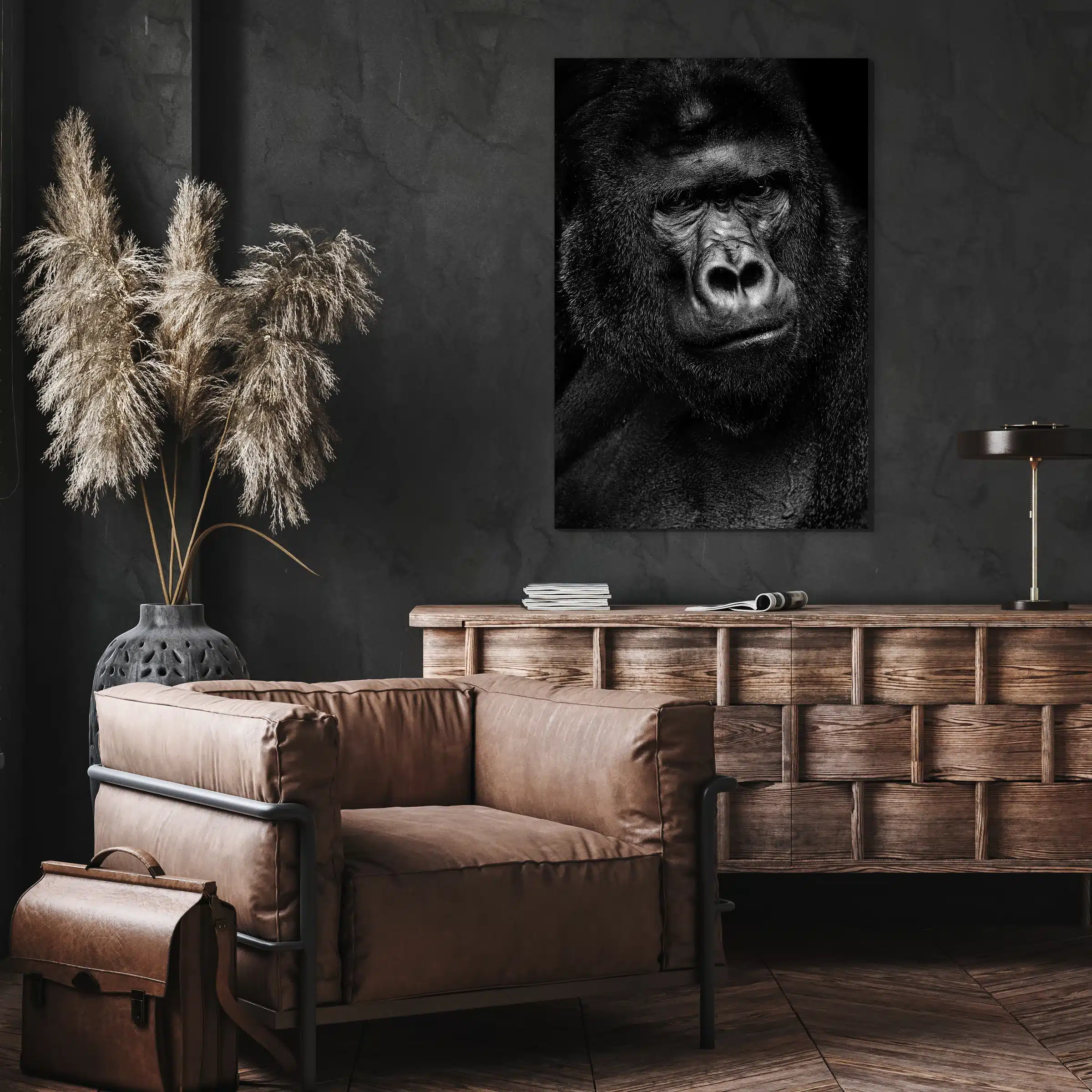 Gorilla portret aan een donkere muur boven een houten dressoir en een leren fauteuil