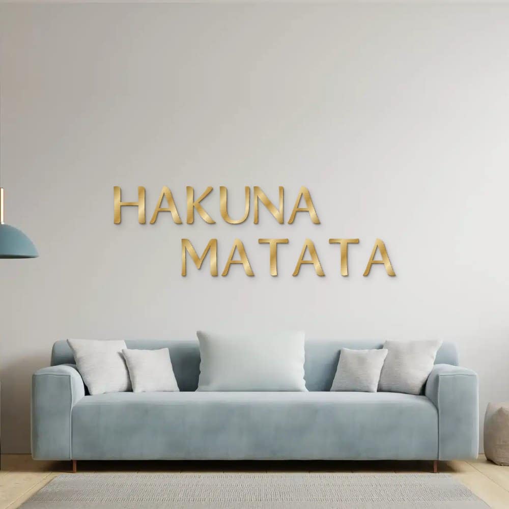 Hakuna Matata in goud geborsteld aluminium aan de muur boven een bank
