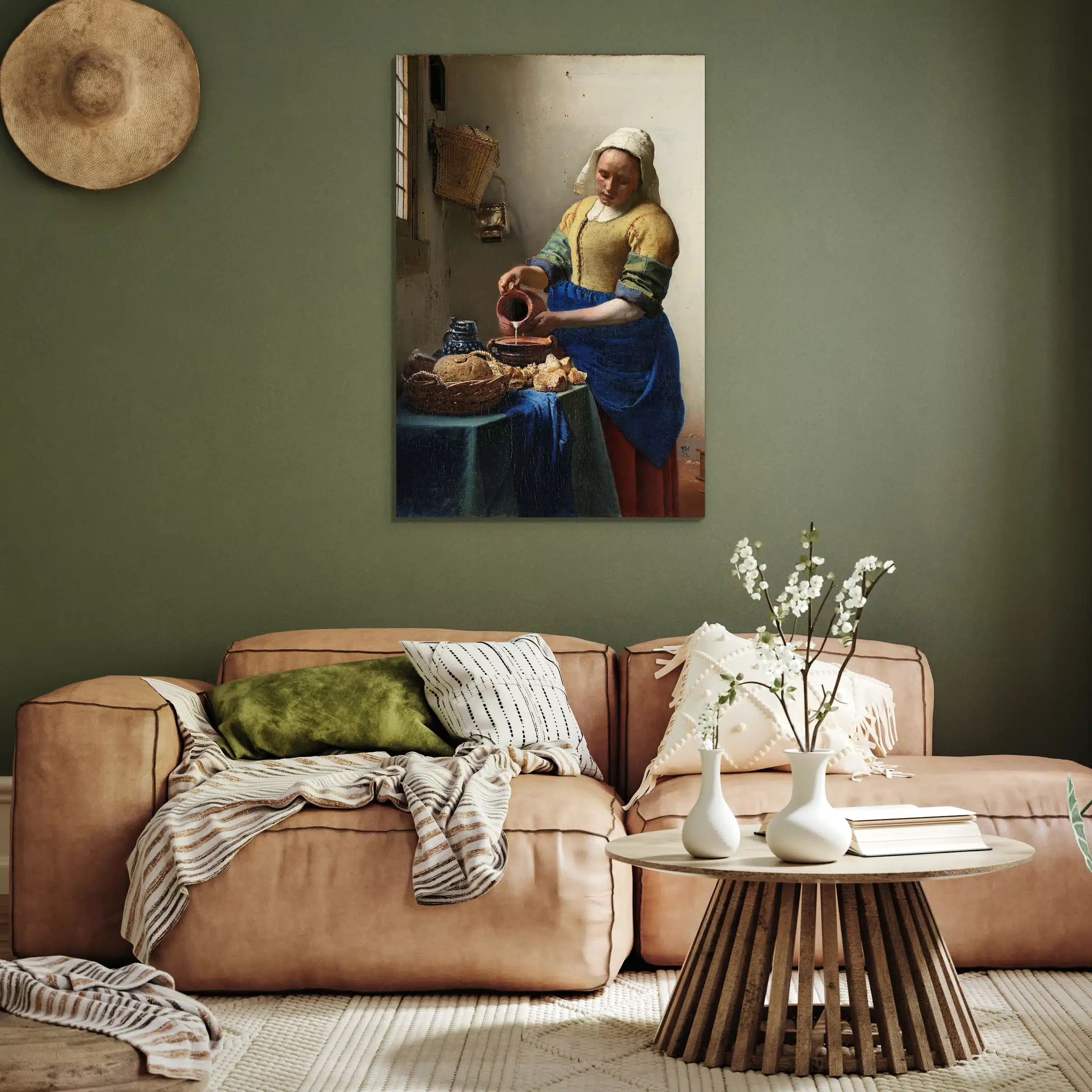 Het melkmeisje van Vermeer aan een olijfgroene muur boven een cognac leren bank