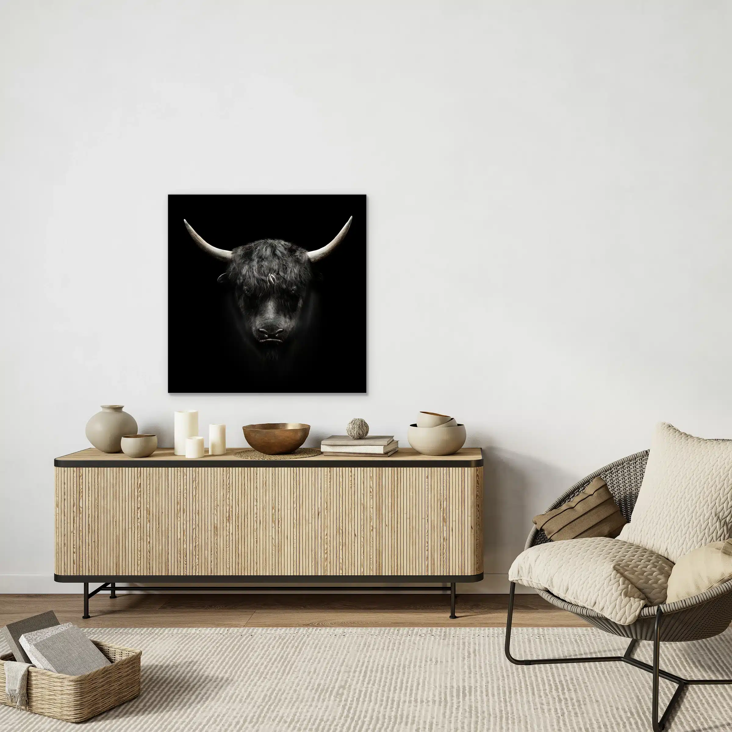 Jak wanddecoratie aan een witte muur boven een houten lamellen dressoir naast een rotan stoel