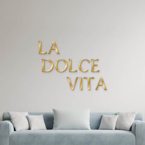 La dolce vita in goud geborsteld aluminium aan de muur boven een bank