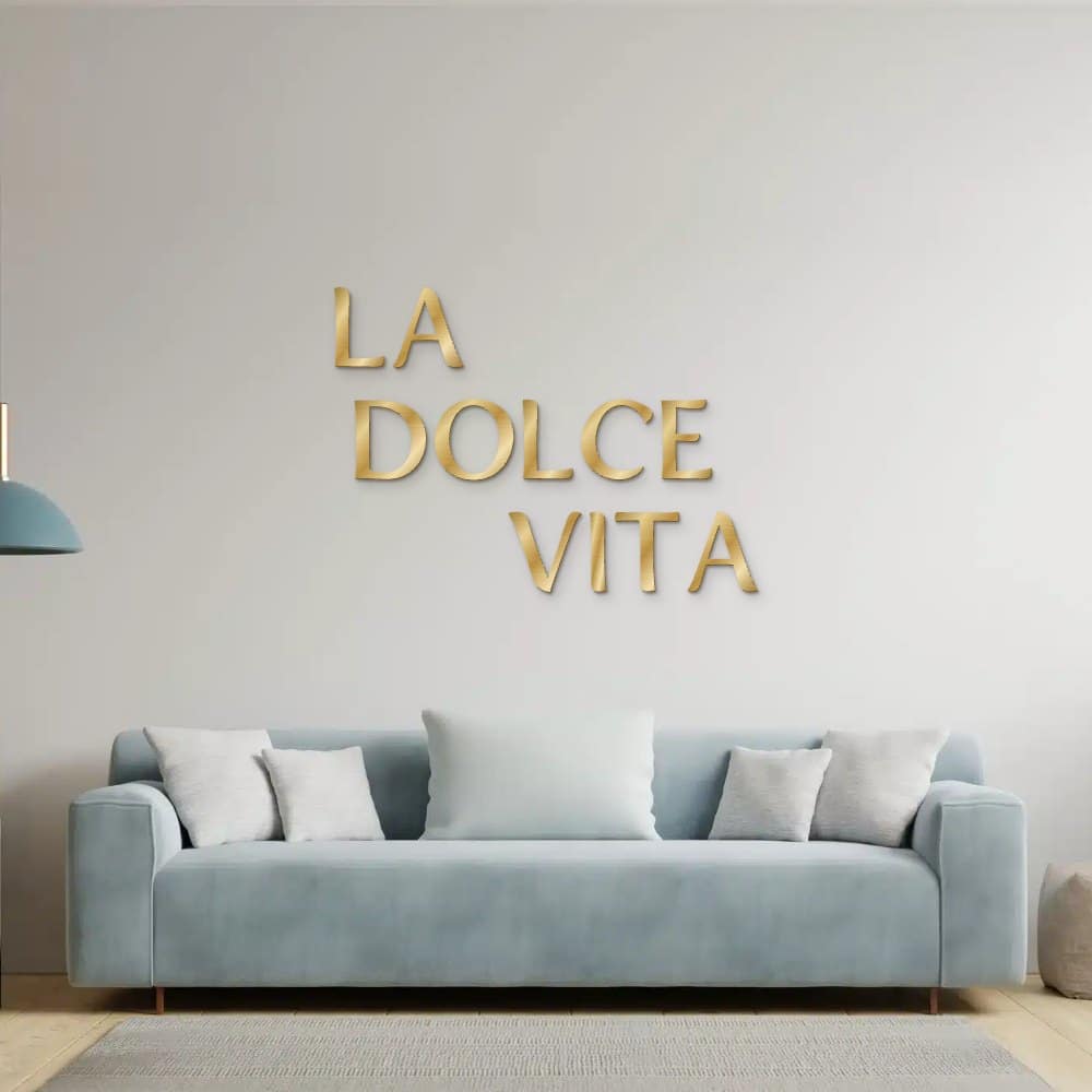 La dolce vita in goud geborsteld aluminium aan de muur boven een bank
