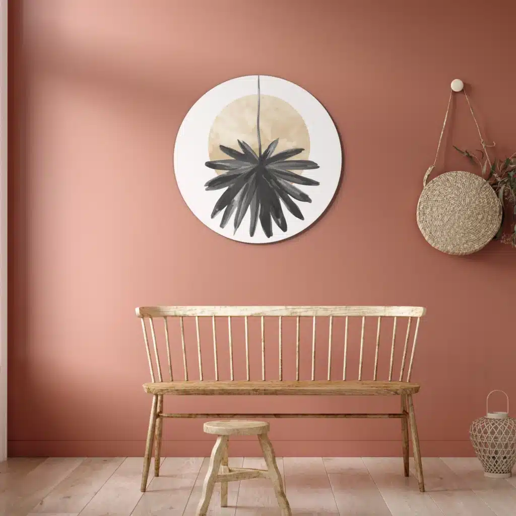 Muurcirkel abstracte hangende bloem boven een houten spijlenbank tegen een terracotta muur