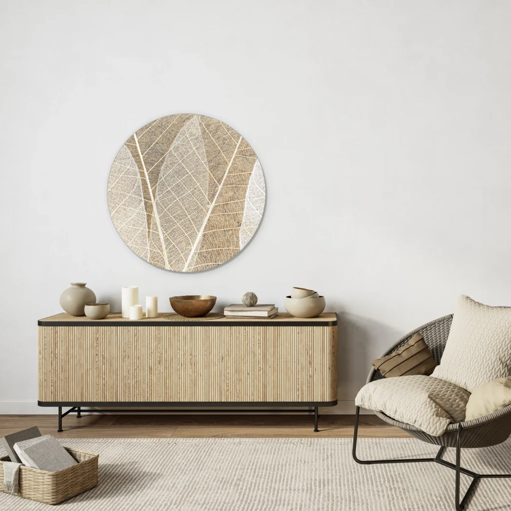 Muurcirkel blad textuur boven een houten lamellendressoir met een loungestoel tegen een witte muur