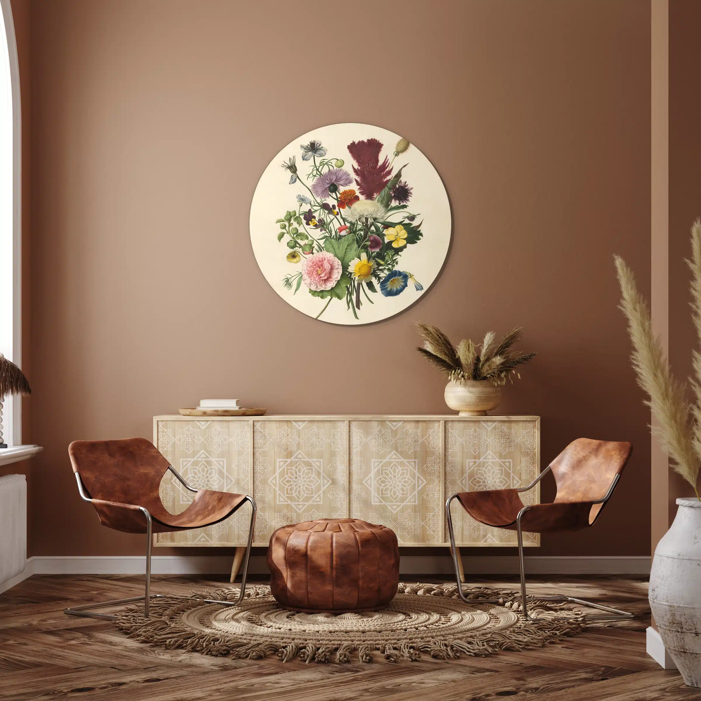 Muurcirkel boeket bloemen boven een licht houten dressoir met rotan stoelen tegen een terracotta muur