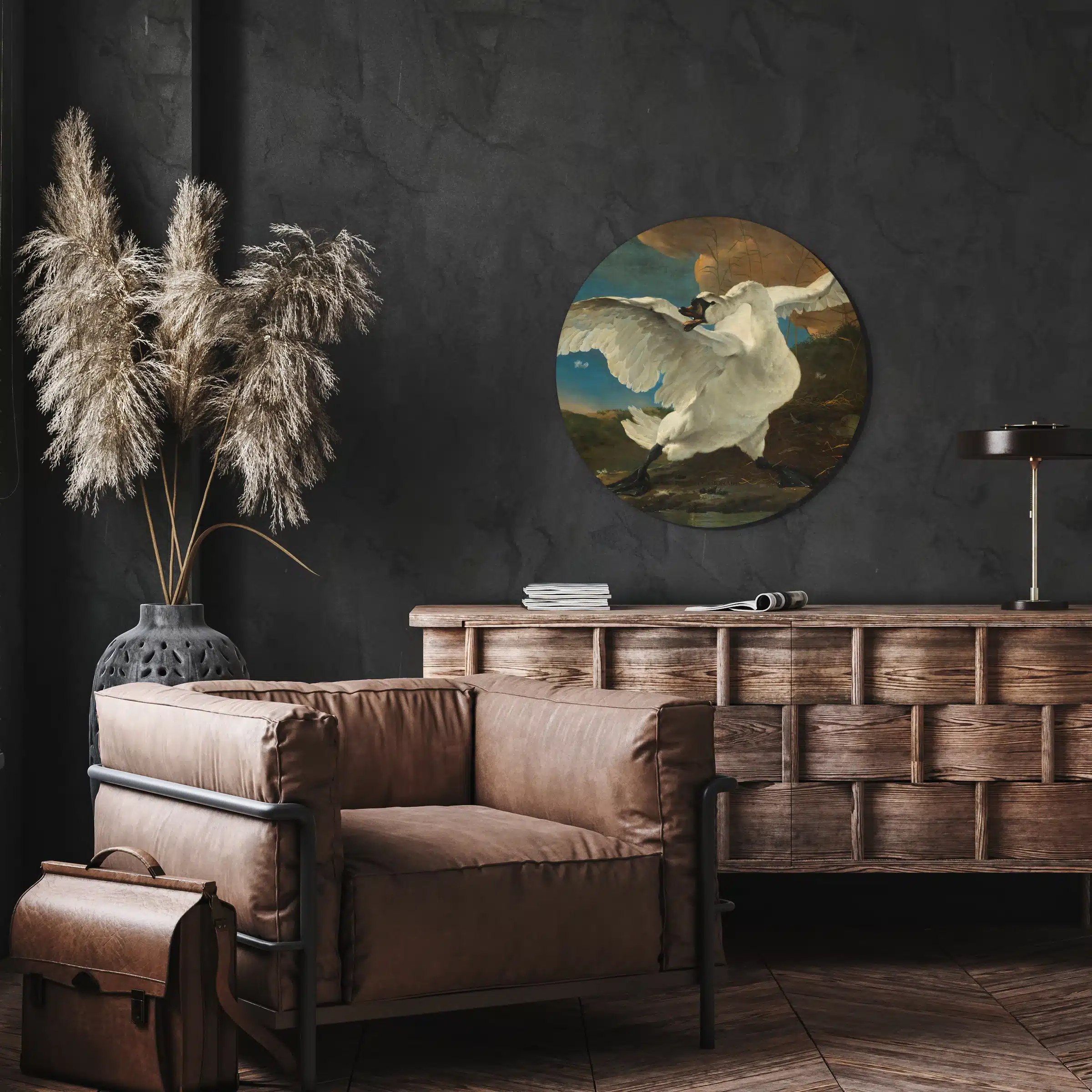 Muurcirkel de bedreigde zwaan van Jan Asselijn aan een antraciet wand boven een houten dressoir en leren fauteuil