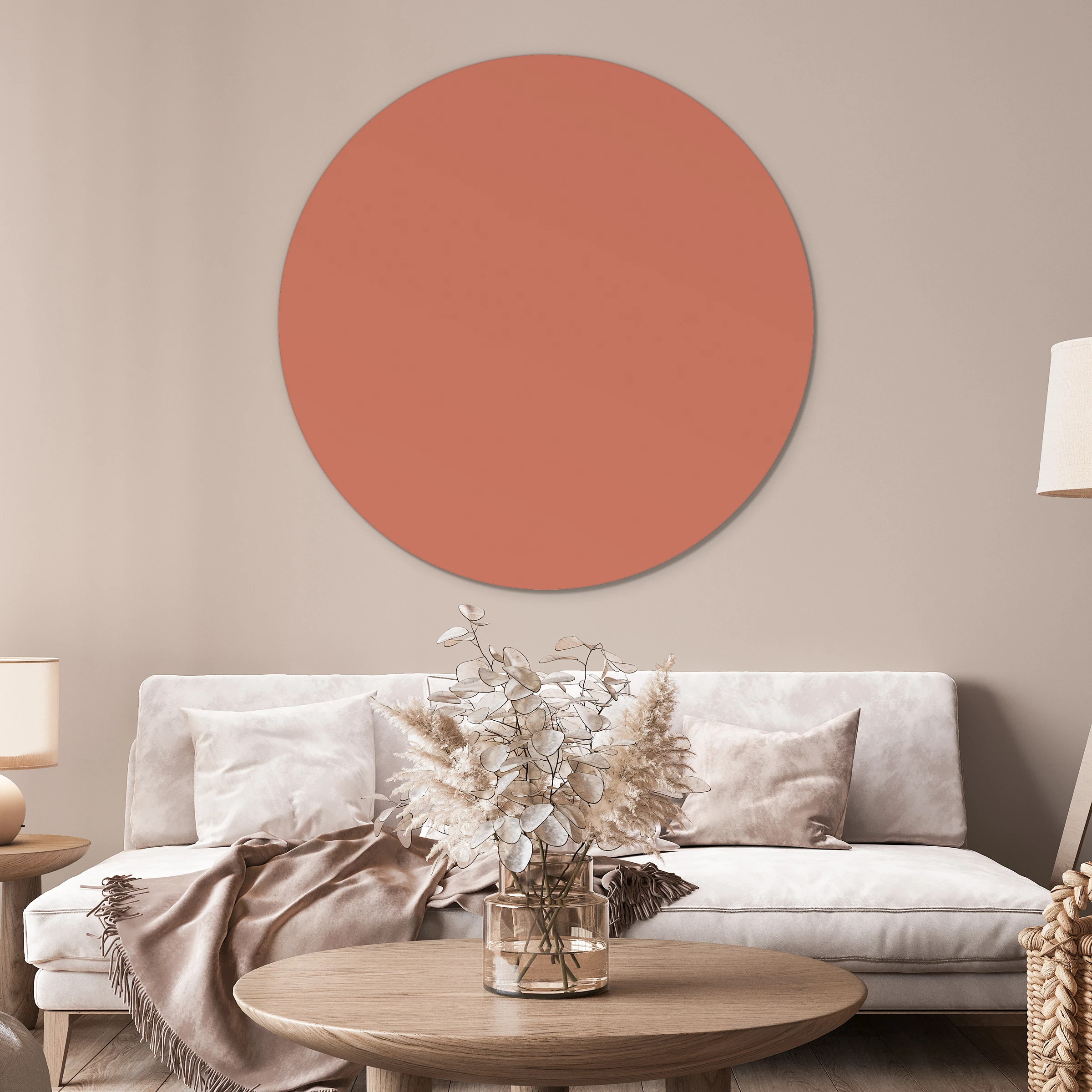 Muurcirkel donker nude pink boven een witte bank met droogbloemen en een houten salontafel