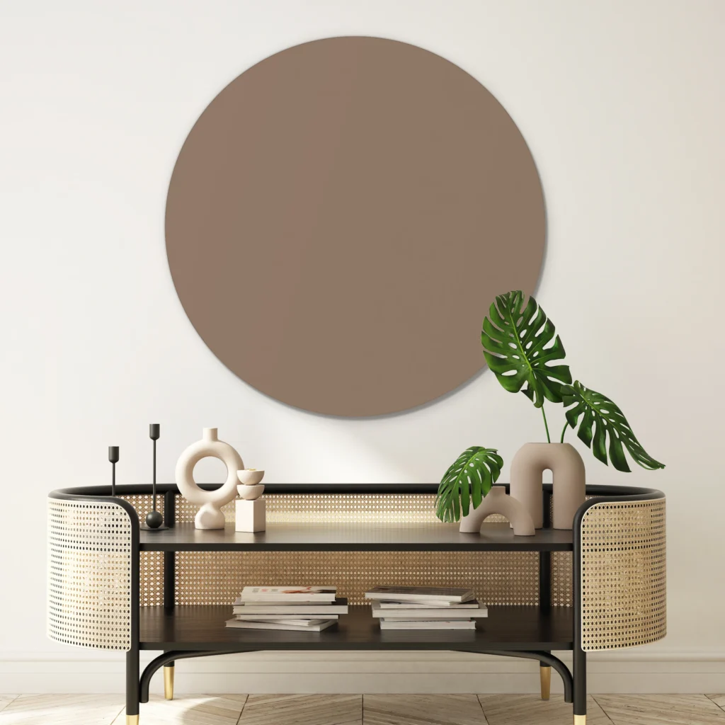 Donker taupe muurcirkel boven een zwarte console met rotan zijkanten en een monstera