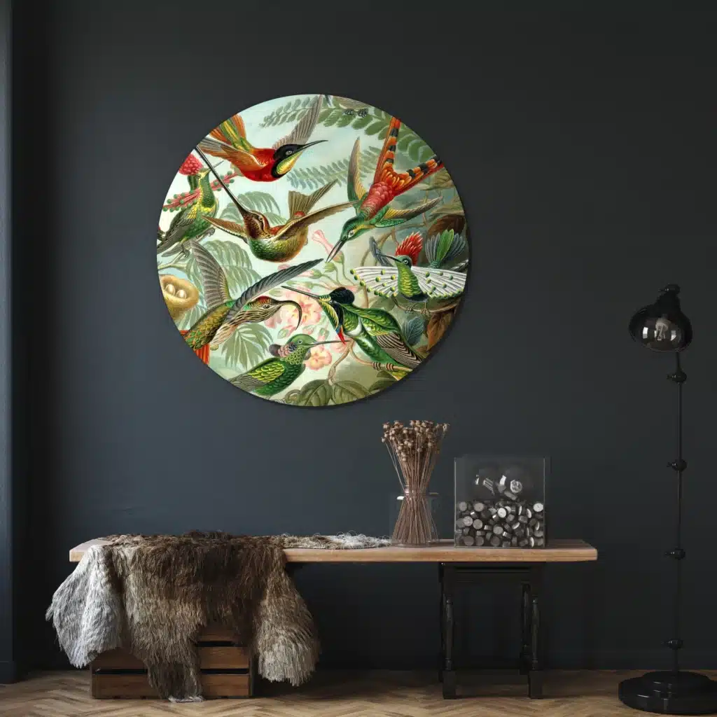 Muurcirkel kolibries van Ernst Haeckel aan een donkerblauwe wand boven een houten console met een vacht
