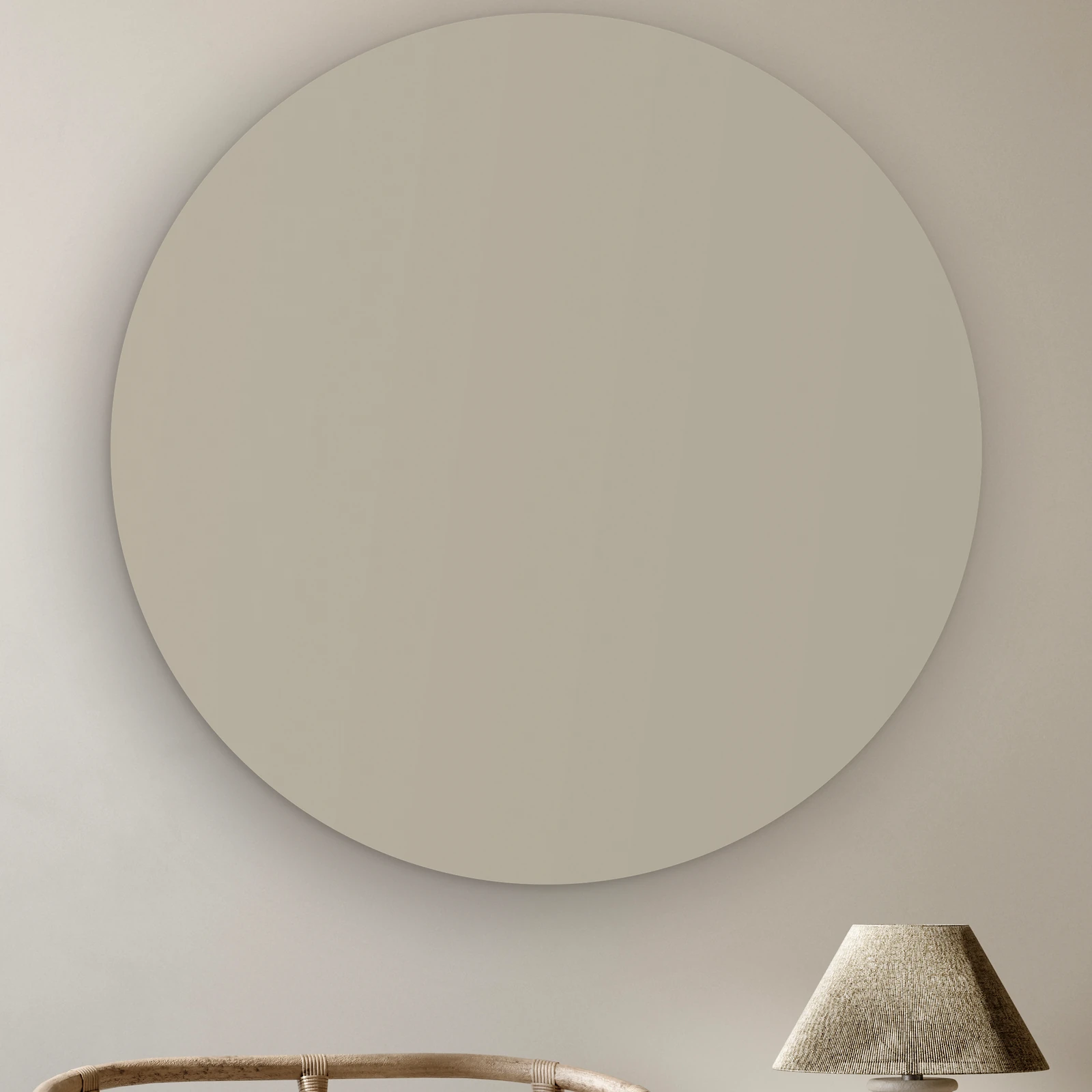 Muurcirkel Licht grijs aan de muur boven een rotan stoel en een tafellamp