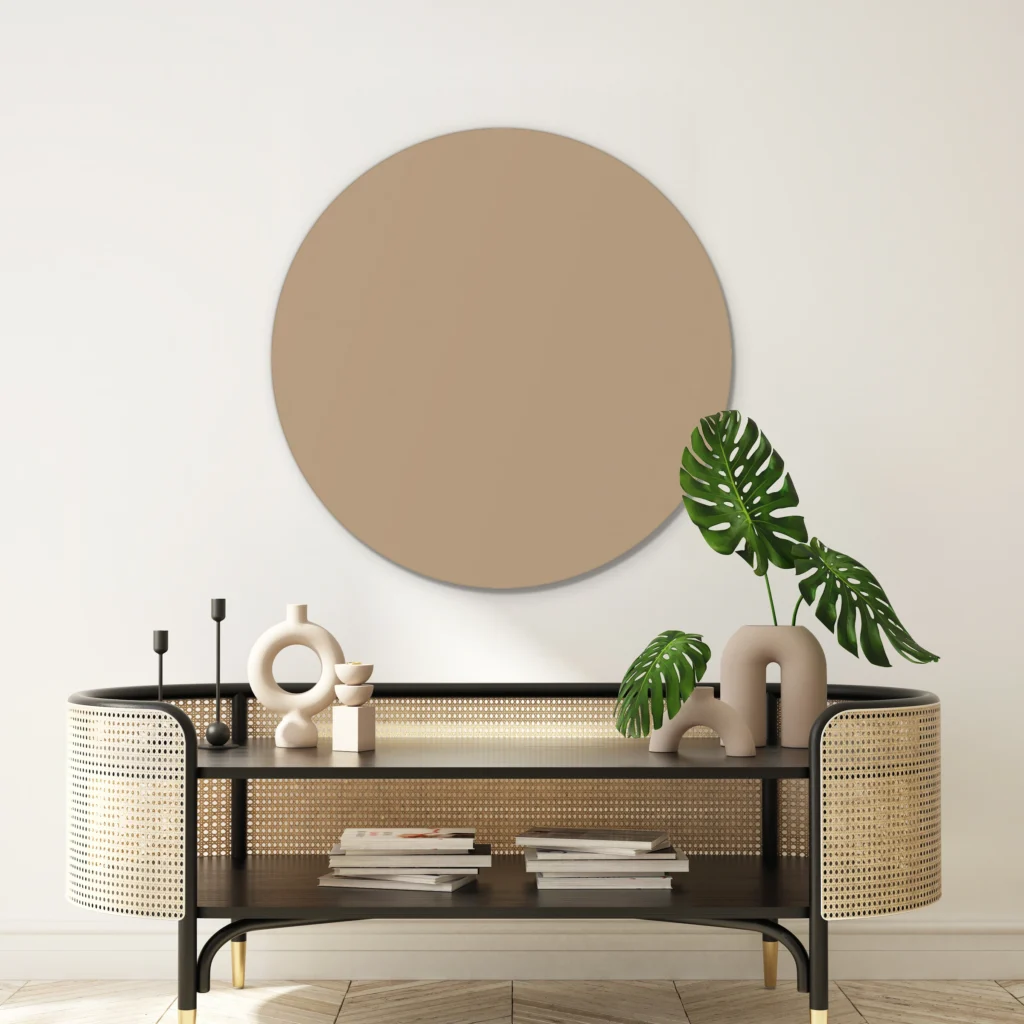 Muurcirkel licht taupe aan een crèmewitte wand boven een rotan console met een monstera