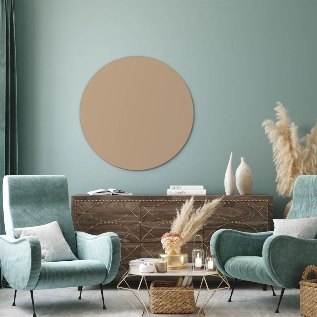 Muurcirkel licht taupe aan een blauwgroene wand boven een donker houten dressoir tussen twee fluwelen fauteuils