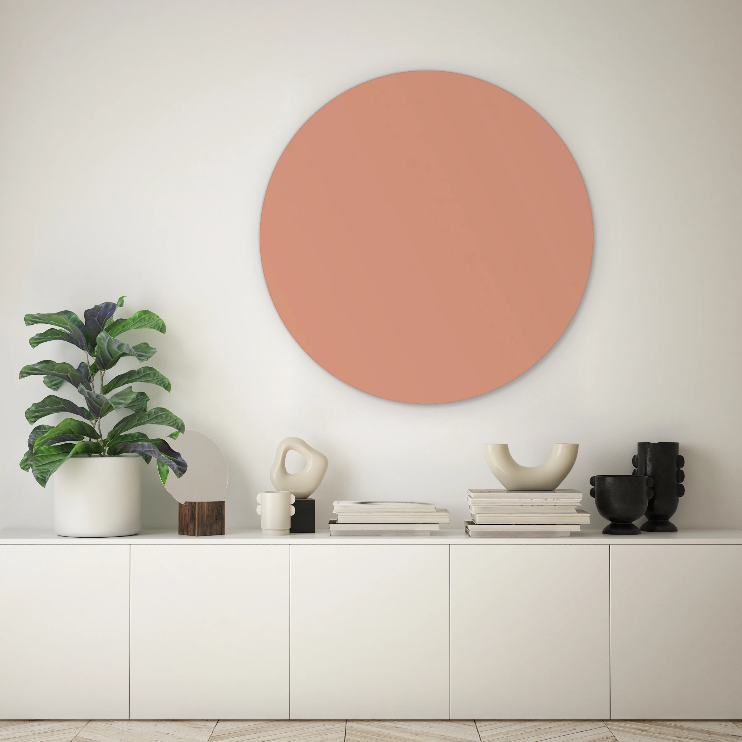 Muurcirkel nude pink boven een lage witte kast met een vioolbladplant tegen een lichte muur
