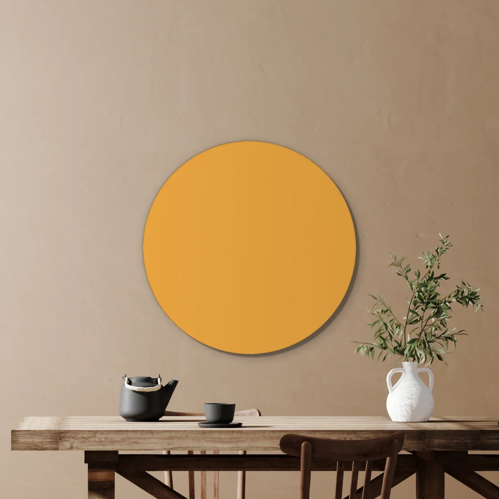 Muurcirkel okergeel boven een houten tafel met een olijftak in een witte kruik
