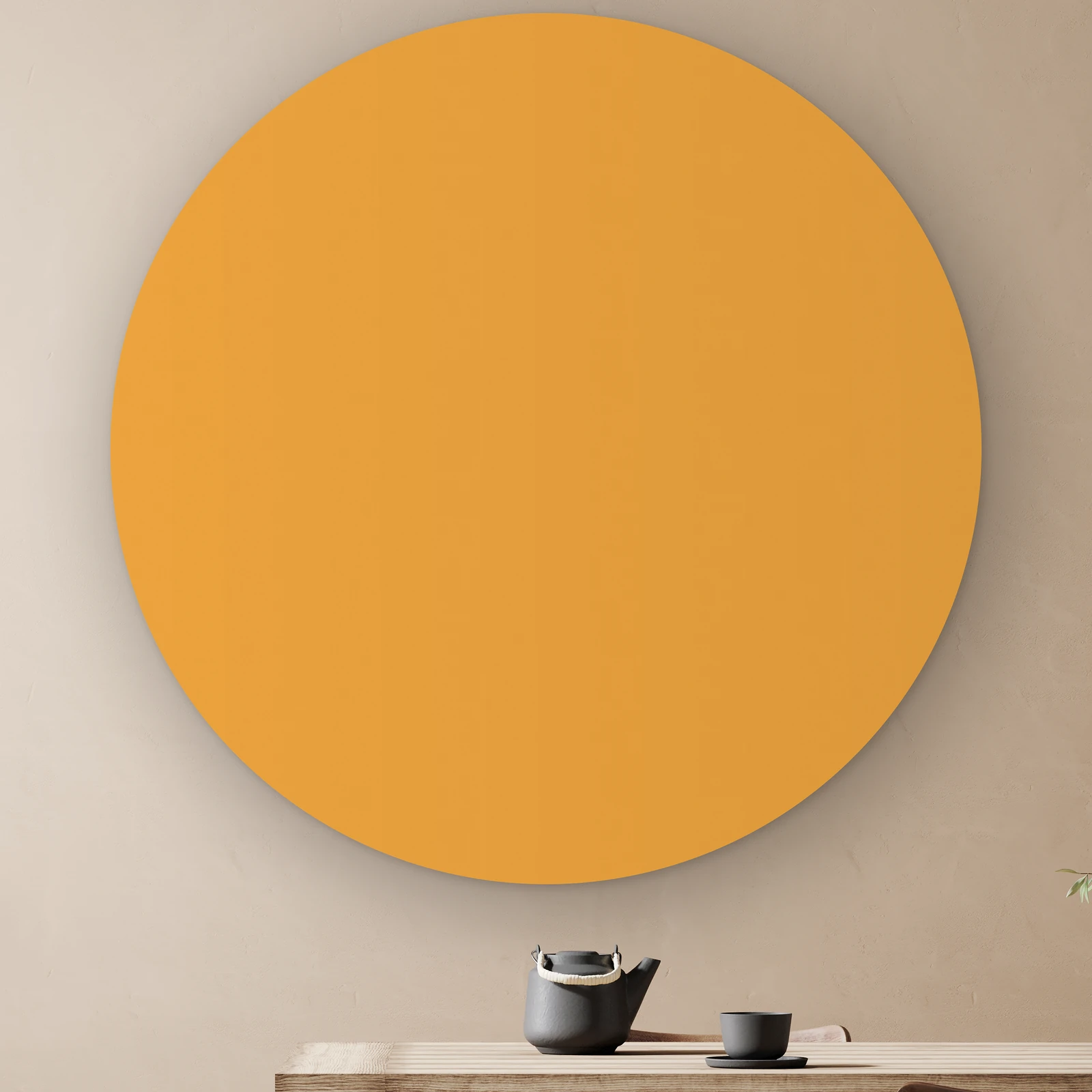 Muurcirkel Okergeel aan de muur boven een houten tafel met theepot