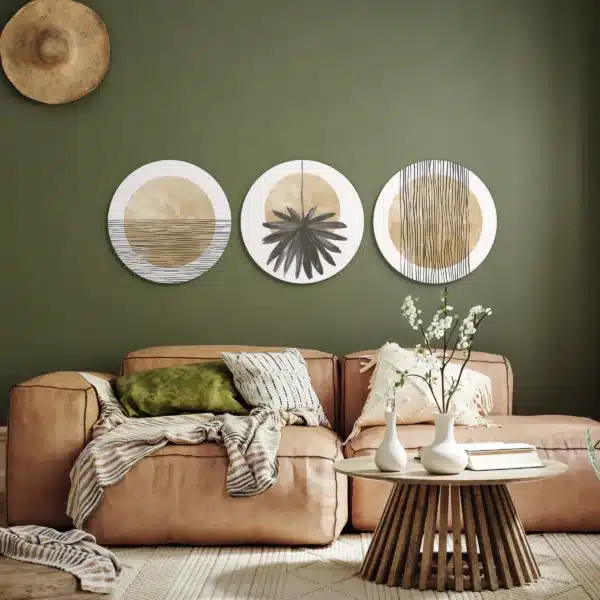 Beige muurcirkel set aan een olijfgroene muur boven een cognackleurige bank