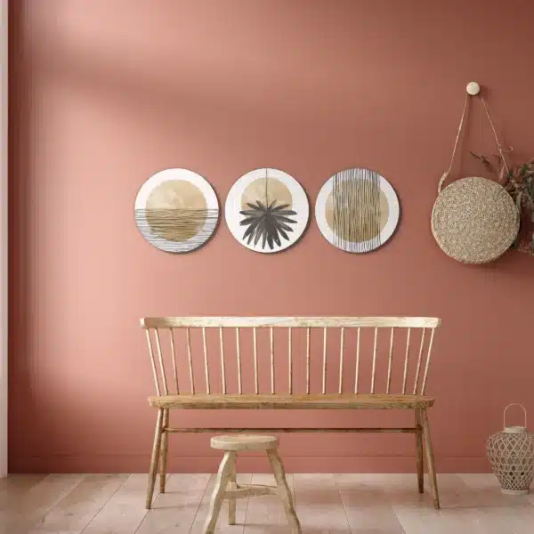 Beige muurcirkel set aan een terracotta muur boven een houten bank