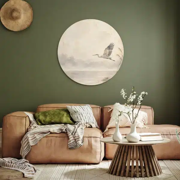 Japandi schilderij vogels als muurcirkel aan een olijfgroene muur boven een cognackleurige bank