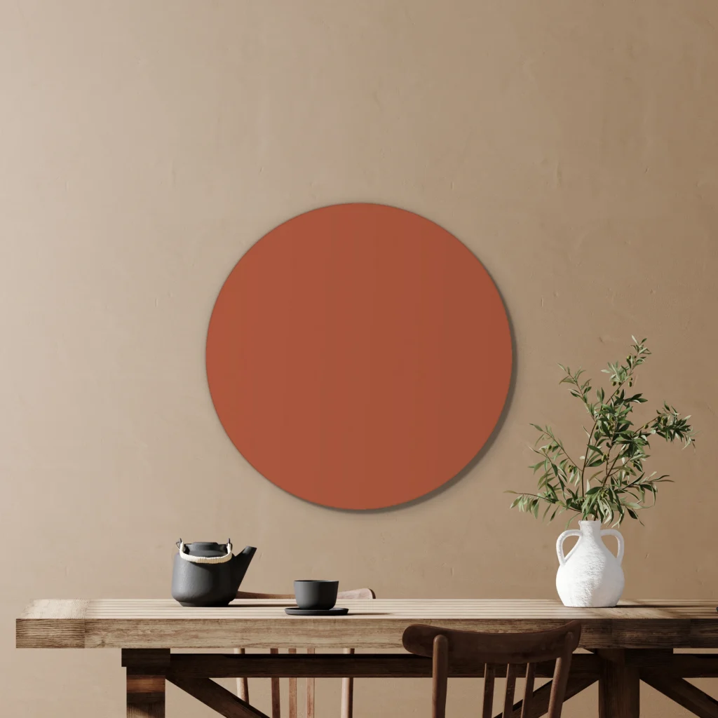 Muurcirkel terracotta boven een houten tafel met een olijftak in een witte kruik, tegen een beige muur