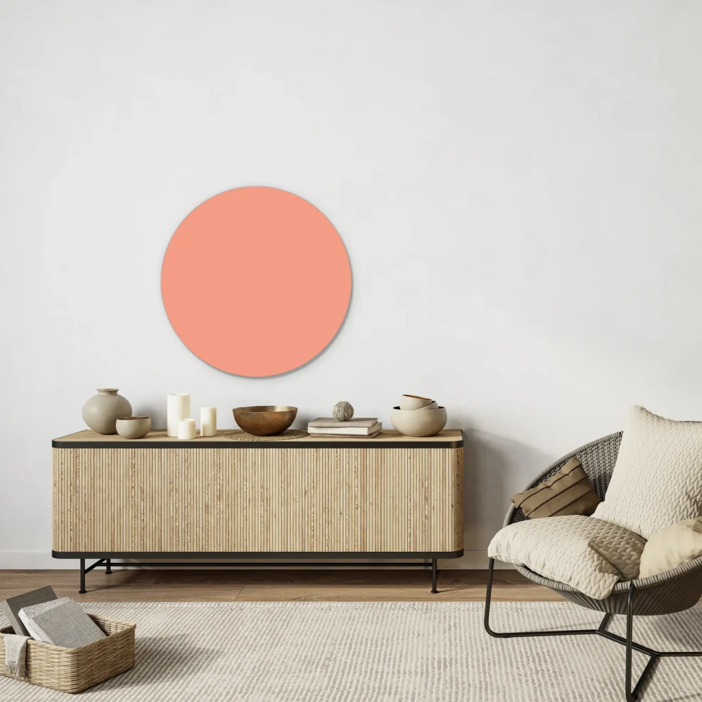 Muurcirkel zalm boven een licht houten lamellen dressoir naast een rotan fauteuil