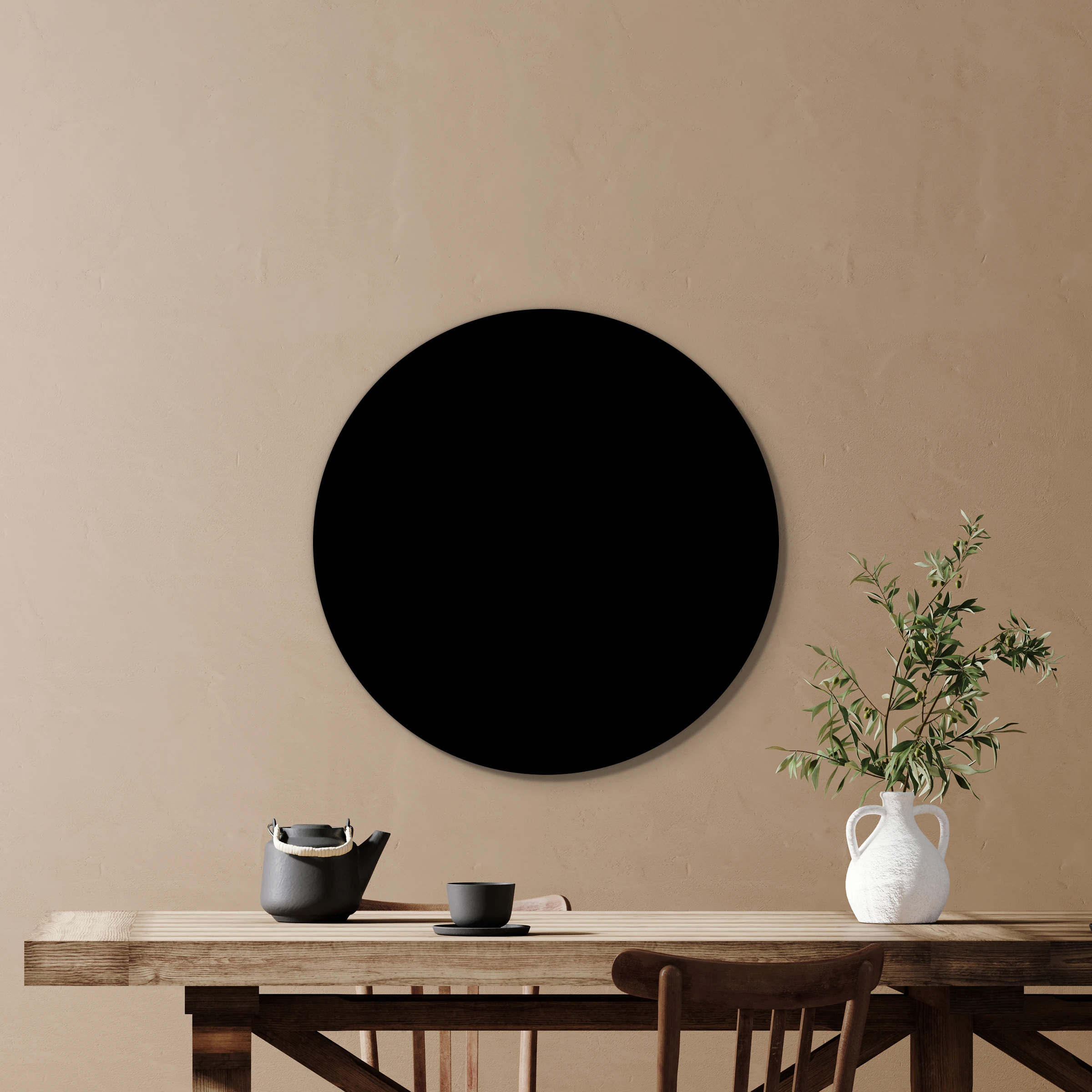 Muurcirkel zwart aan een zandbeige wand boven een houten tafel met een plant in een witte kruik